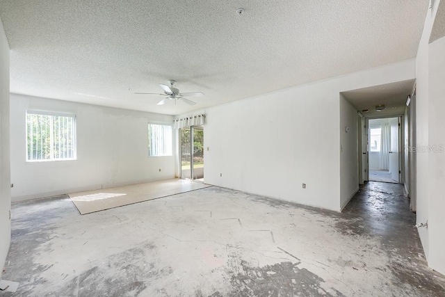 spare room with a textured ceiling, unfinished concrete floors, and a ceiling fan