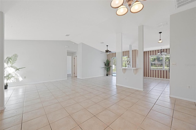 empty room with visible vents, baseboards, lofted ceiling, light tile patterned flooring, and ceiling fan with notable chandelier