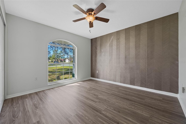 empty room with ceiling fan, baseboards, and wood finished floors