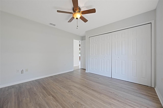 unfurnished bedroom with visible vents, wood finished floors, a closet, baseboards, and ceiling fan