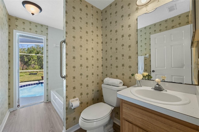 bathroom with vanity, wood finished floors, baseboards, wallpapered walls, and toilet