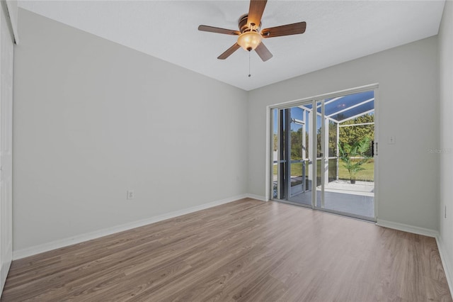 empty room featuring a ceiling fan, wood finished floors, baseboards, and a sunroom