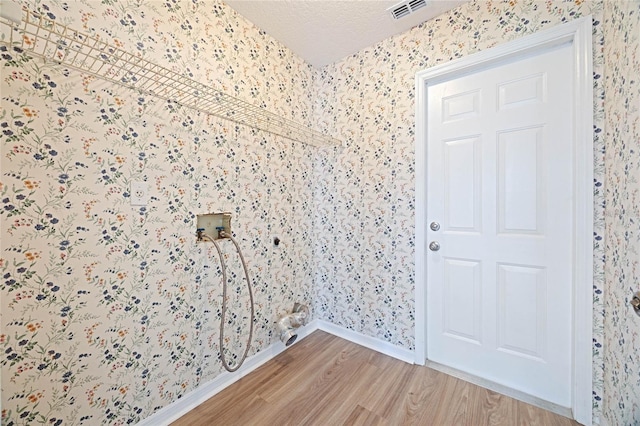 clothes washing area with visible vents, wallpapered walls, washer hookup, laundry area, and light wood-style flooring