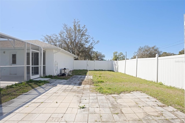 view of yard with a fenced backyard, glass enclosure, and a patio