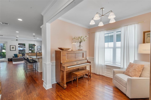 sitting room with crown molding, wood finished floors, and visible vents