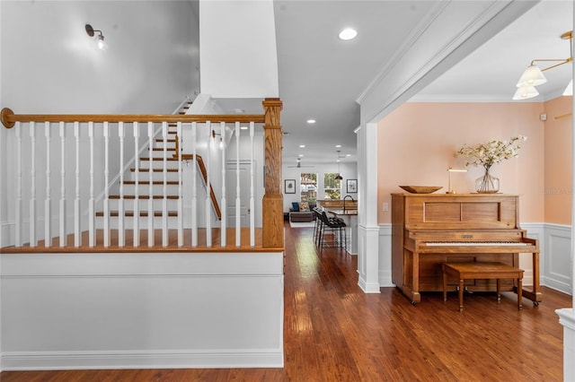 hall featuring crown molding, stairway, wainscoting, wood finished floors, and a decorative wall