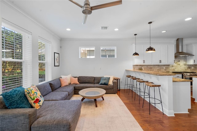 living area with visible vents, recessed lighting, ceiling fan, dark wood-type flooring, and crown molding