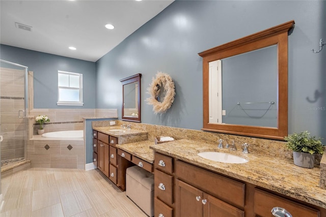 bathroom with visible vents, a shower stall, a garden tub, double vanity, and a sink