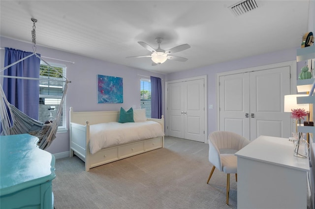 bedroom with visible vents, two closets, carpet, and a ceiling fan