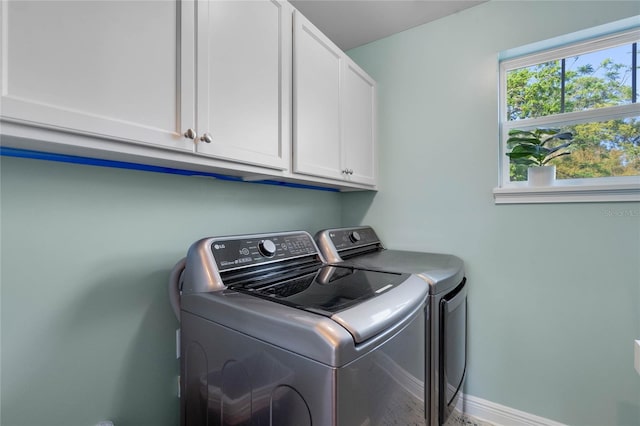 laundry room featuring washing machine and dryer, cabinet space, and baseboards