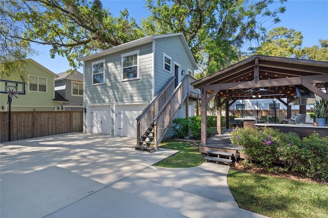 view of front of property featuring fence, a gazebo, concrete driveway, a garage, and stairs