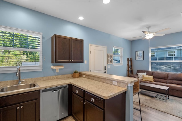 kitchen featuring a breakfast bar area, a peninsula, a sink, dark brown cabinets, and stainless steel dishwasher