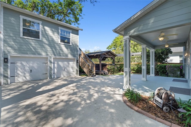 view of side of property featuring a gazebo, a ceiling fan, a garage, and driveway