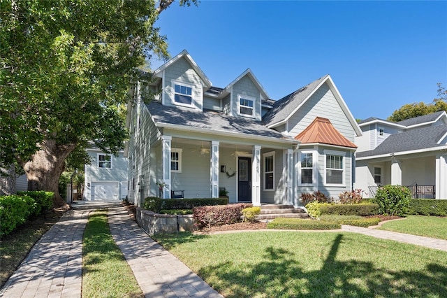 view of front facade with a porch, a front yard, and metal roof