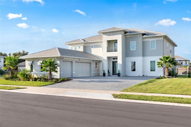 view of front of home with stucco siding, decorative driveway, fence, a front yard, and an attached garage