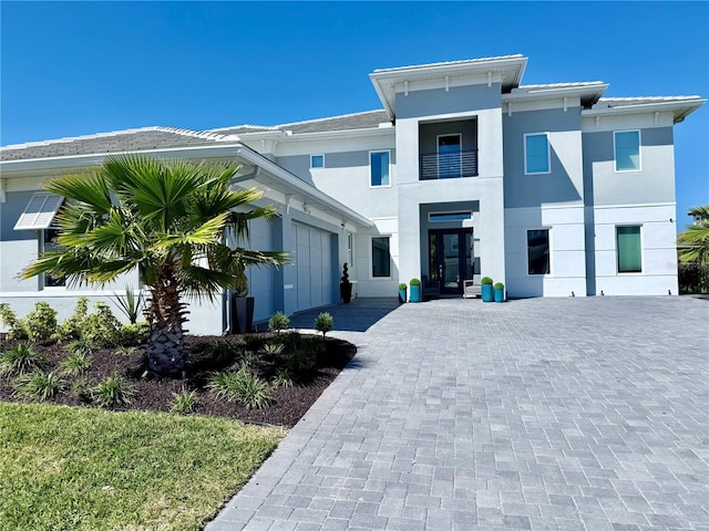 view of front facade featuring decorative driveway, an attached garage, and stucco siding