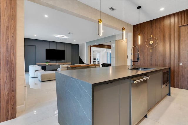 kitchen featuring visible vents, modern cabinets, a sink, stainless steel appliances, and a large island with sink