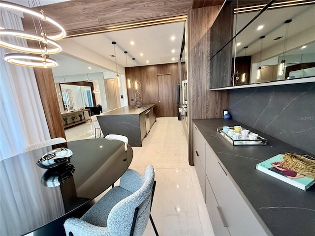 kitchen featuring dark countertops, decorative backsplash, hanging light fixtures, marble finish floor, and modern cabinets