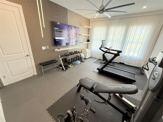 workout area featuring wallpapered walls, a textured ceiling, and a ceiling fan