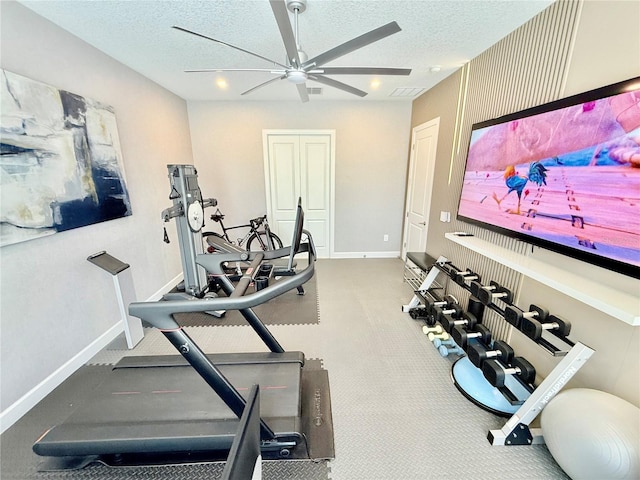 workout area with visible vents, baseboards, a textured ceiling, and a ceiling fan