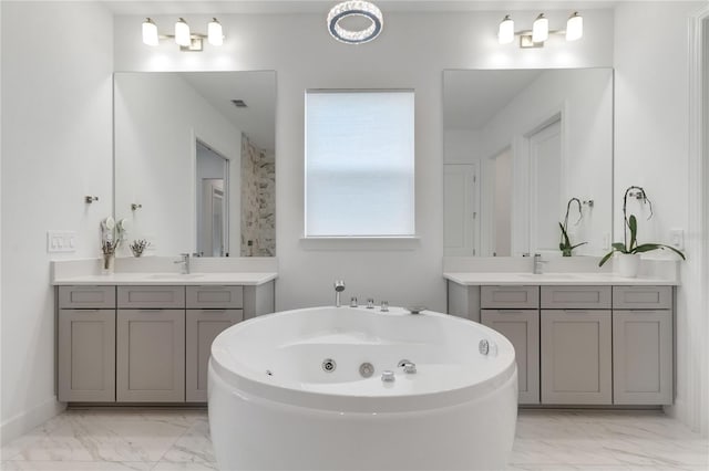 bathroom featuring visible vents, marble finish floor, a jetted tub, and a sink