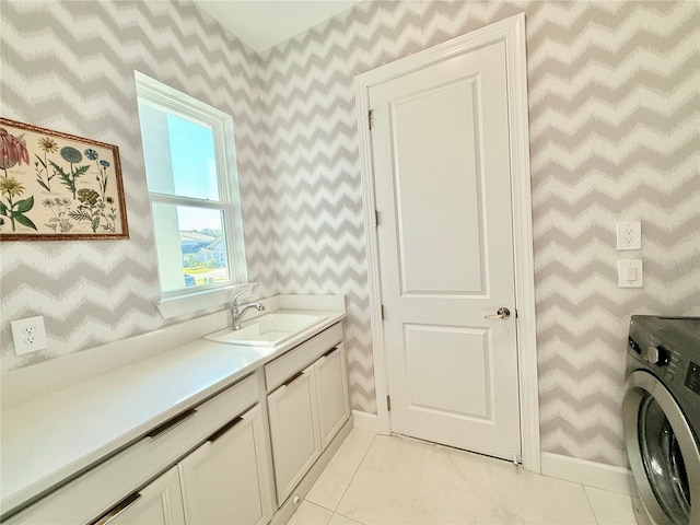 clothes washing area with a sink, cabinet space, wallpapered walls, light tile patterned floors, and washer / dryer