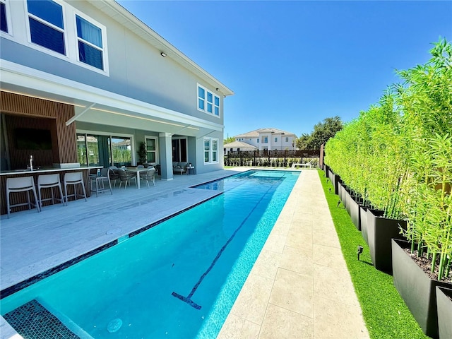 view of pool with outdoor dry bar, a fenced in pool, fence, a patio area, and a sink