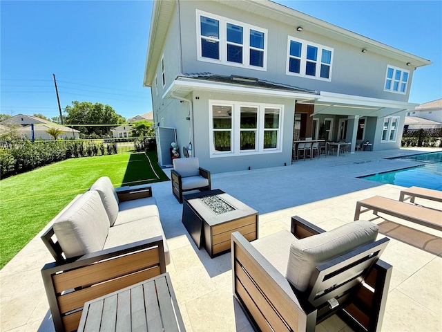 back of house with a fenced in pool, an outdoor living space with a fire pit, stucco siding, a yard, and a patio area