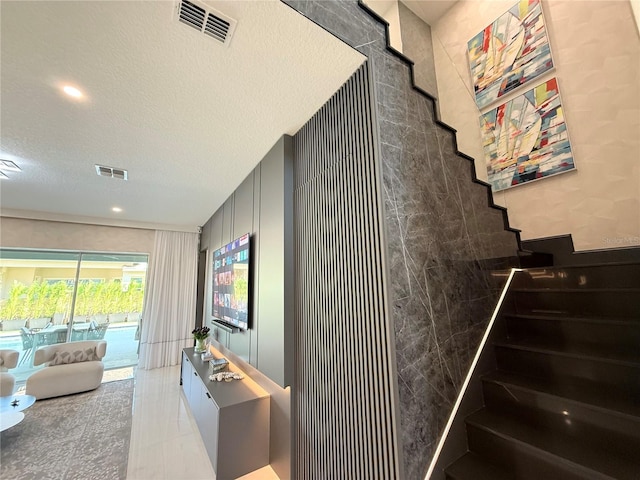 stairway featuring tile patterned floors, visible vents, and a textured ceiling