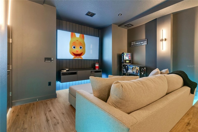 home theater room with visible vents, a textured ceiling, and light wood-style flooring