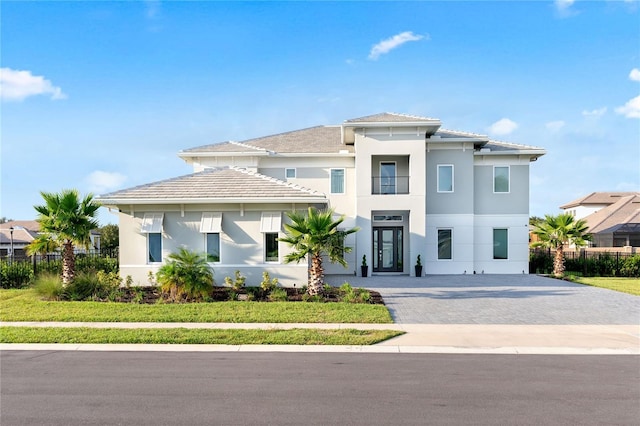 view of front of house featuring stucco siding, decorative driveway, and fence