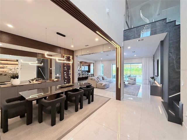 tiled dining area with visible vents, recessed lighting, and a towering ceiling