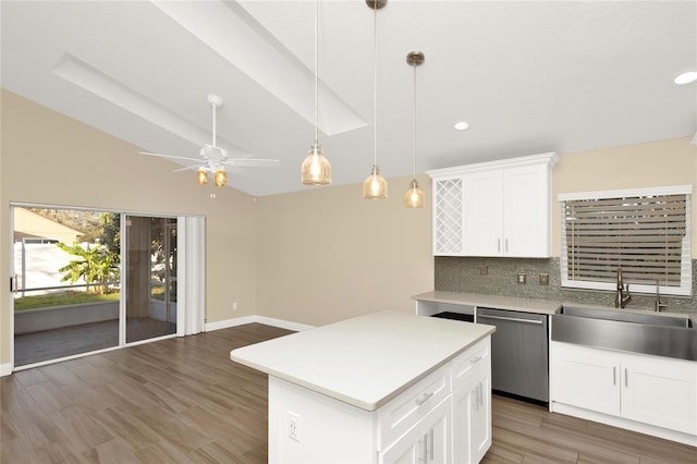 kitchen with a sink, backsplash, wood finished floors, light countertops, and dishwasher