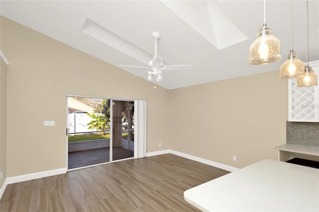 kitchen featuring ceiling fan, baseboards, wood finished floors, and vaulted ceiling