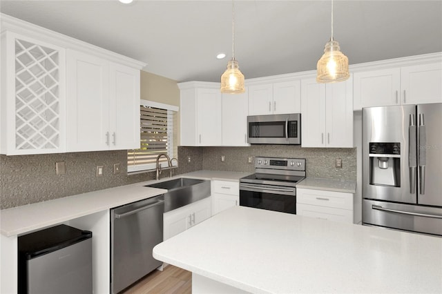 kitchen featuring a sink, stainless steel appliances, light countertops, white cabinets, and tasteful backsplash