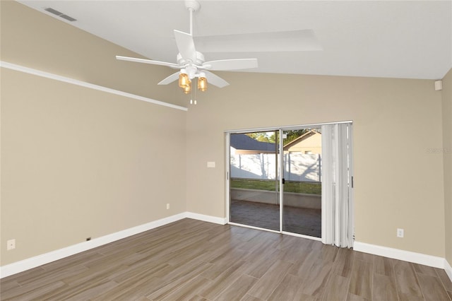 empty room featuring vaulted ceiling, baseboards, visible vents, and wood finished floors