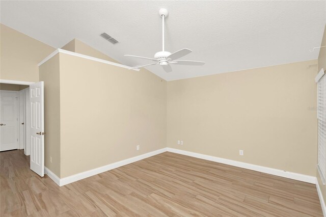 spare room featuring visible vents, light wood-style flooring, baseboards, and lofted ceiling