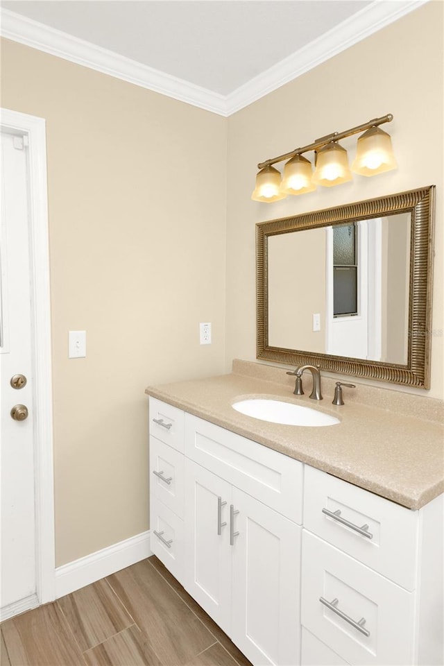 bathroom featuring wood finished floors, vanity, baseboards, and ornamental molding