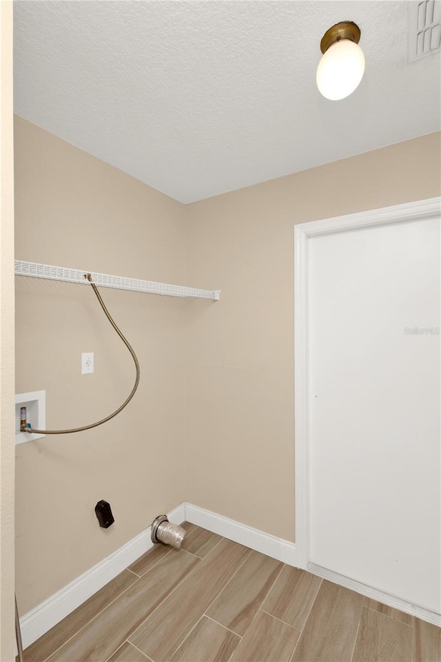 laundry room with hookup for a washing machine, baseboards, wood tiled floor, laundry area, and a textured ceiling