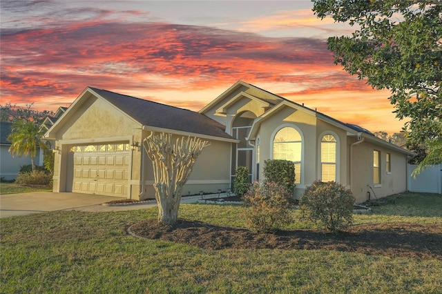 ranch-style home featuring stucco siding, driveway, a yard, and an attached garage