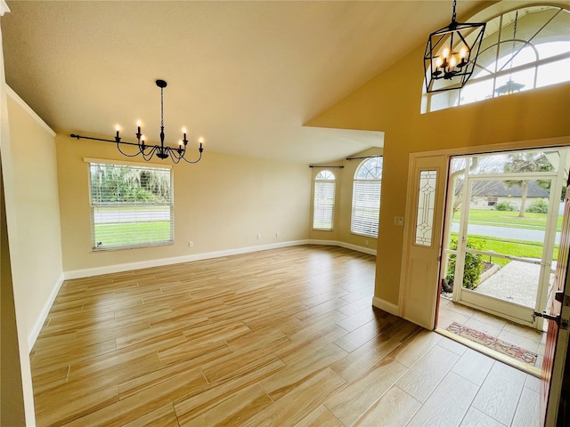 foyer featuring vaulted ceiling, light wood-style floors, baseboards, and a chandelier