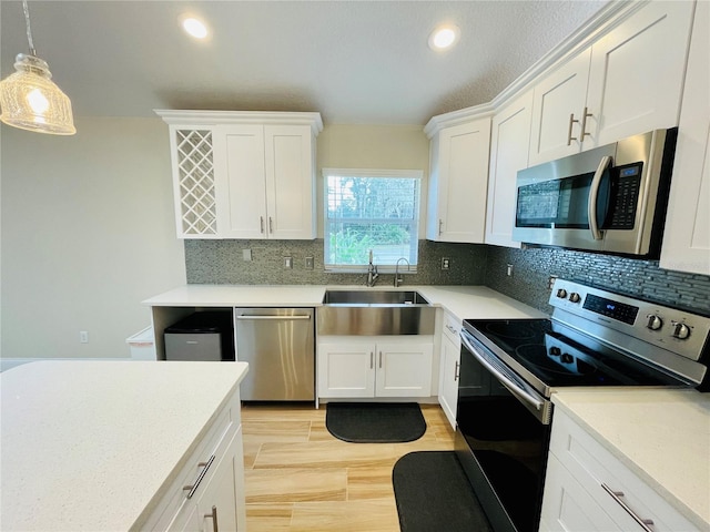 kitchen with a sink, appliances with stainless steel finishes, white cabinets, and light countertops