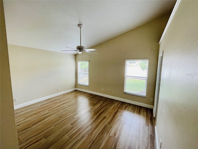 empty room featuring a ceiling fan, lofted ceiling, wood finished floors, and baseboards