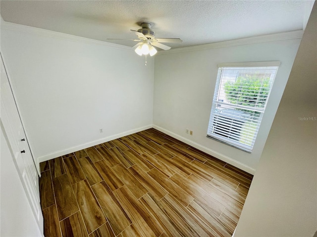 spare room featuring ornamental molding, a ceiling fan, a textured ceiling, dark wood-style floors, and baseboards