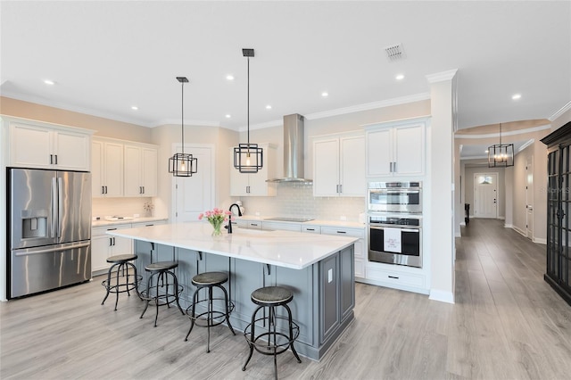 kitchen with visible vents, stainless steel appliances, white cabinets, a kitchen bar, and wall chimney exhaust hood