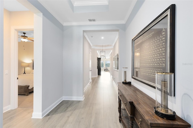 hallway featuring light wood-type flooring, baseboards, visible vents, and crown molding