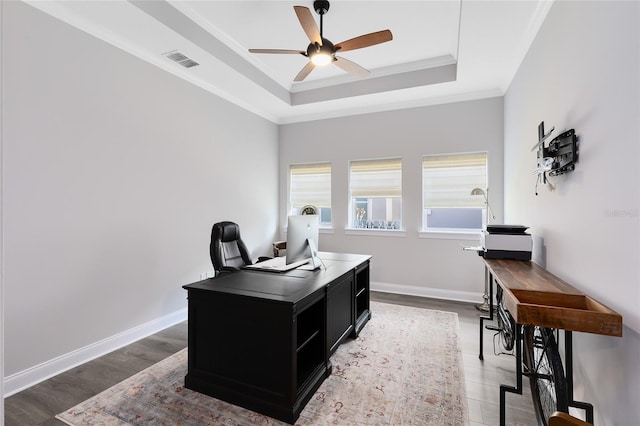 office featuring visible vents, baseboards, a tray ceiling, ornamental molding, and a ceiling fan