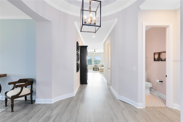 hallway with baseboards, crown molding, and light wood-style floors