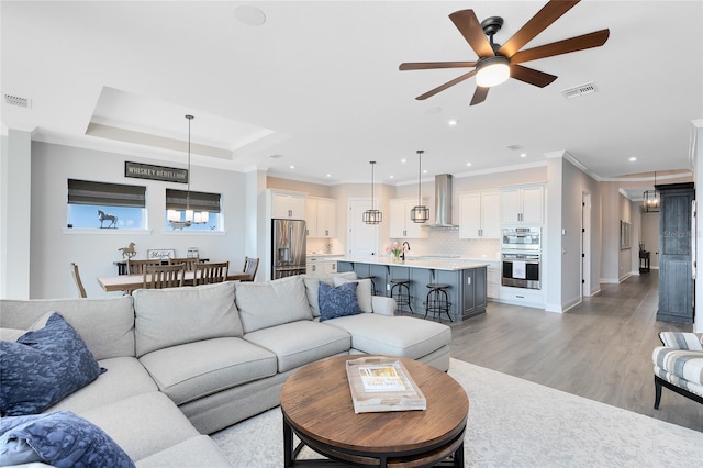 living area featuring recessed lighting, visible vents, crown molding, and light wood finished floors