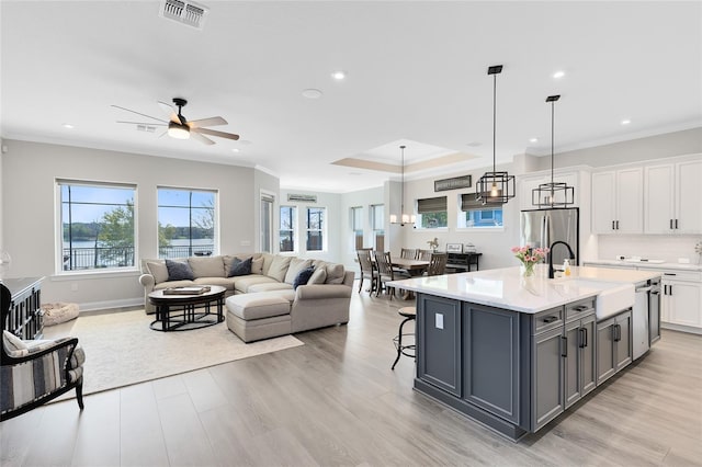 kitchen with visible vents, gray cabinetry, open floor plan, stainless steel refrigerator with ice dispenser, and a sink